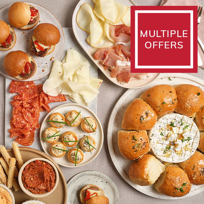 Overhead shot of cold meats, cheeses, olives, bread sticks and dips