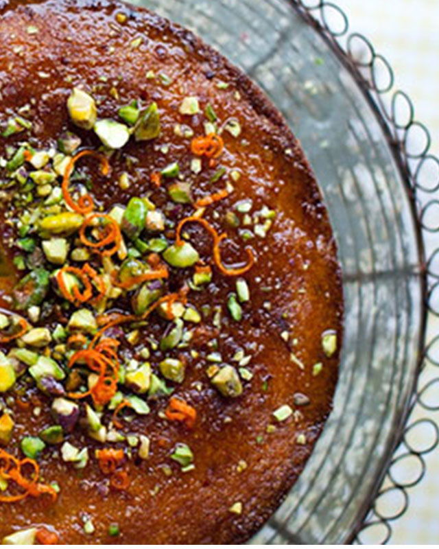 Orange and polenta cake garnished with orange slices and herbs