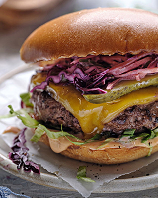 Stacked burgers with fresh toppings on a summer table