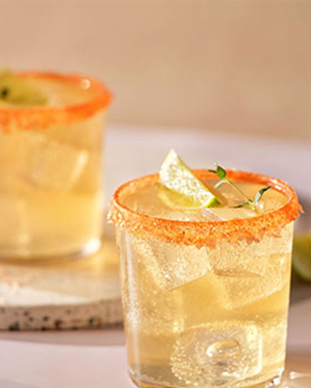 Citrusy Irish Whiskey Paloma in a salted-rim glass with lime wedge and rosemary sprig garnish