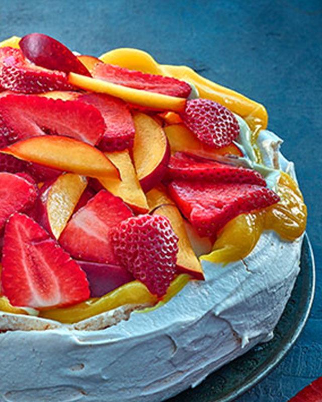 Pavlova topped with whipped pistachio cream and fresh summer fruits