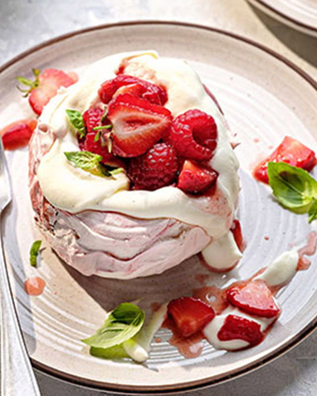 Mini pavlova clouds topped with sweetened cream and fresh mixed berries