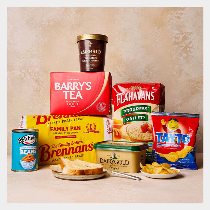 A colorful assortment of Irish food items including tea, bread, oats, beans, chocolate dessert, and crisps, arranged attractively.