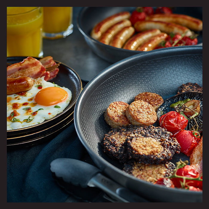 A hearty breakfast featuring eggs, bacon, sausages, and grilled tomatoes