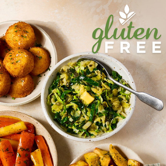 Top-down view of gluten-free meal with fried balls, saut&eacute;ed greens with butter, roasted carrots, and crispy potato wedges.