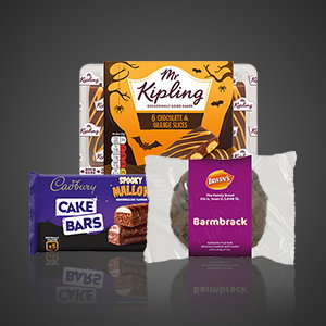 Assorted Halloween bakery treats including Mr Kipling chocolate and orange slices, Cadbury cake bars, Spooky Mallows and Irwin's barmbrack displayed against a dark background.