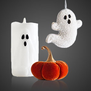 Halloween homeware decorations including a white ghost LED candle, a hanging ghost ornament and a small orange pumpkin displayed against a dark background.