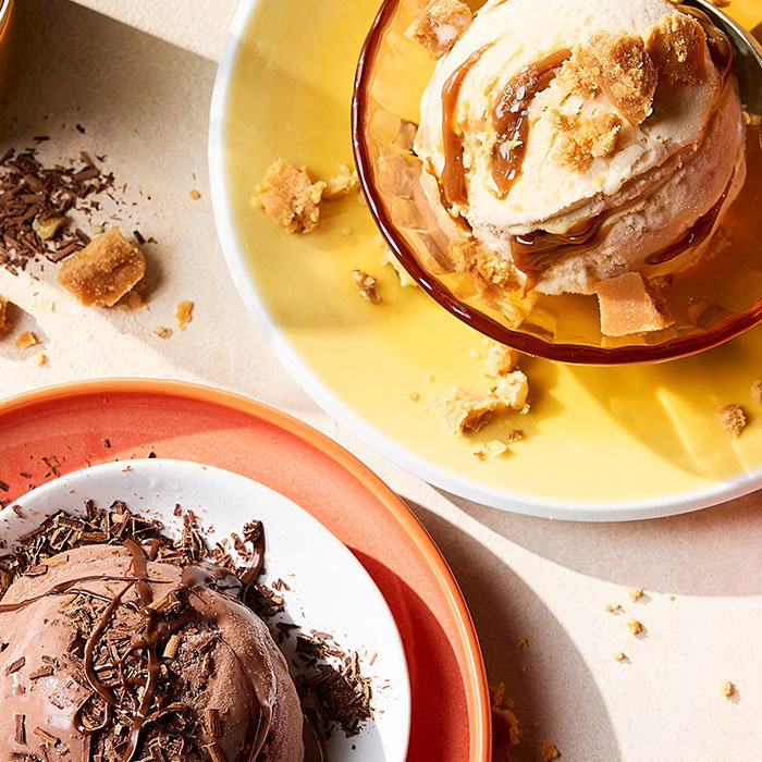 Two bowls of ice cream with crumbled cookies and chocolate shavings on colorful plates in bright natural light. Links to summer dessert products.