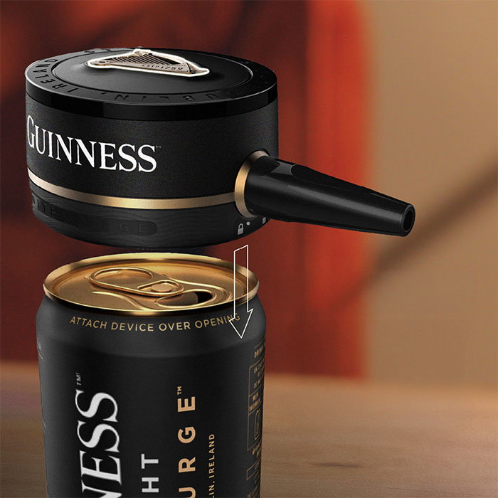 Guinness-branded device attaching over the opening of a black Guinness beer can, shown with an arrow indicating placement.