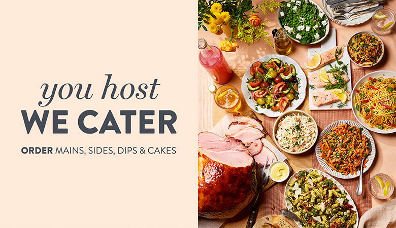 Catering spread with sliced ham, salads, pasta dishes, dips, and drinks arranged on a table alongside the text "You host, we cater."