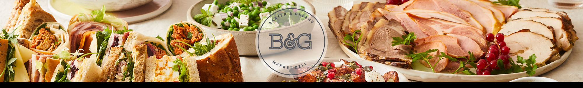 An elegant catering spread featuring sandwiches, salads, sliced meats, charcuterie, bread, and various accompaniments arranged on a white surface. The Baxter & Greene logo is displayed on a white transparent circle in the centre of the image.