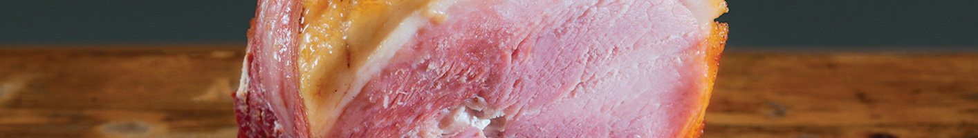 Close-up of a thick-cut raw ham steak with pink meat and white fat layer, positioned on a wooden cutting board showing the natural marbling and texture of the cured pork.