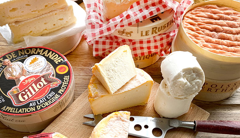 French cheese selection including soft-ripened cheeses like Camembert and Brie, with traditional French packaging and a cheese knife on a wooden cutting board