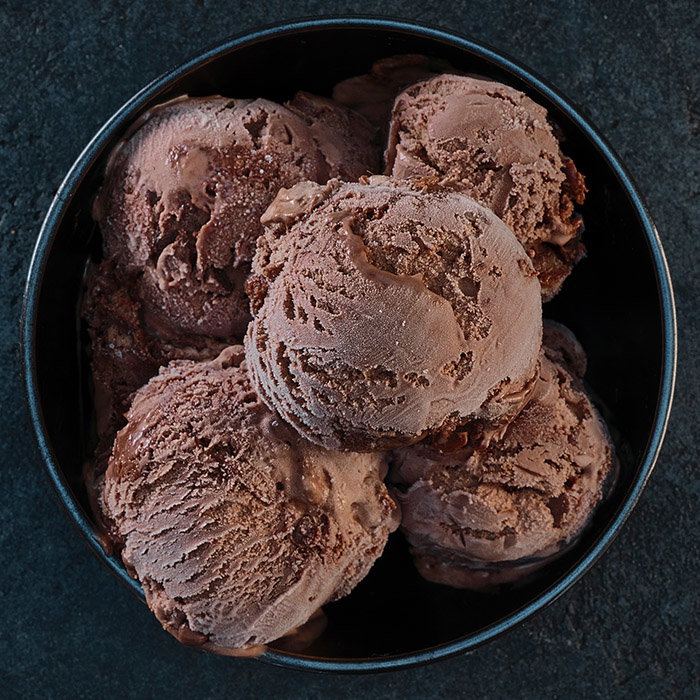 A black bowl filled with several scoops of rich chocolate ice cream, showcasing a creamy texture and frosty surface.