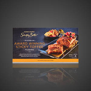 Pack of Dunnes Stores Simply Better handmade award winning sticky toffee pudding dessert, with sliced pudding and berry garnish on the packaging, on a dark background