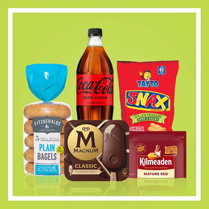 Selection of grocery products including plain bagels, Coca-Cola Zero Sugar, Tayto Snax potato puffs, Magnum Classic ice cream and Kilmeaden Mature Red cheddar cheese on a green background