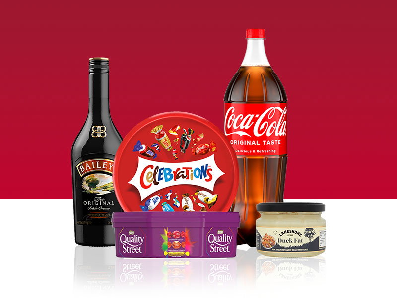 Promotional product display featuring a bottle of Baileys Original Irish Cream, a tub of Celebrations chocolates, a tub of Quality Street chocolates, a large bottle of Coca-Cola Original Taste, and a jar of duck fat on a red and white background.