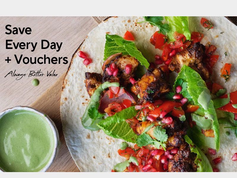 Grilled chicken wrap with fresh vegetables, pomegranate seeds, and herbs served with green sauce. Text reads 'Save Every Day + Vouchers' and 'Always Better Value' promoting daily savings and discount offers.