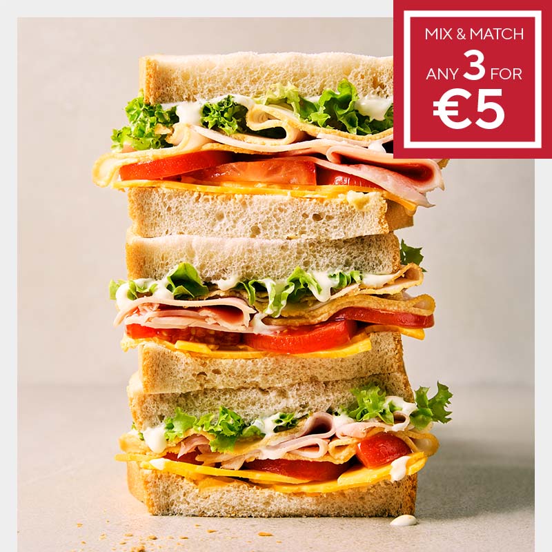Stacked sandwich with fresh lettuce, tomato, ham, cheese, and mayo between slices of bread. Promo in the corner: "Mix & Match any 3 for €5".