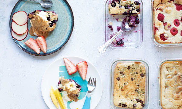 Plates with berry-topped pancakes and fresh fruit slices, including apples and strawberries, create a colourful and inviting dessert scene.
