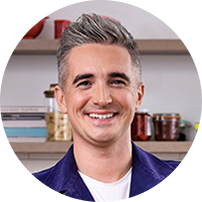 Portrait of chef Donal Skehan smiling in a kitchen setting.